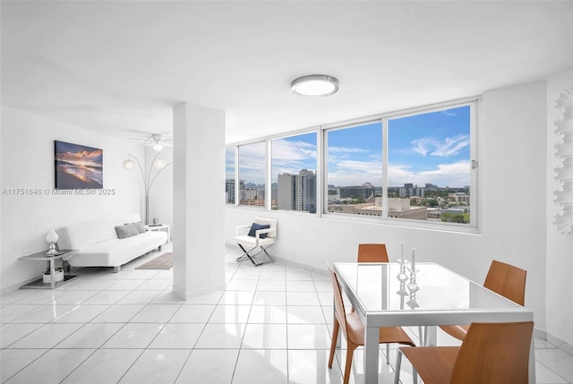 dining room featuring ceiling fan, light tile patterned flooring, a wealth of natural light, and a city view