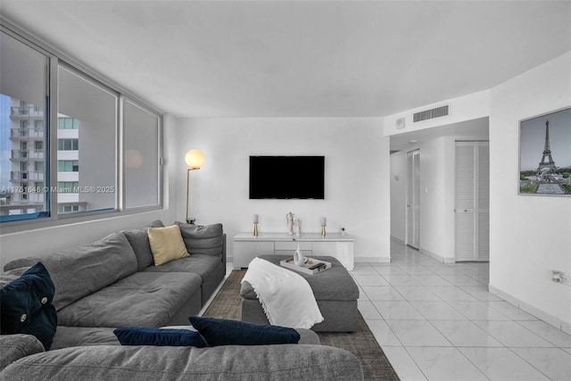 living room with light tile patterned flooring, visible vents, and baseboards