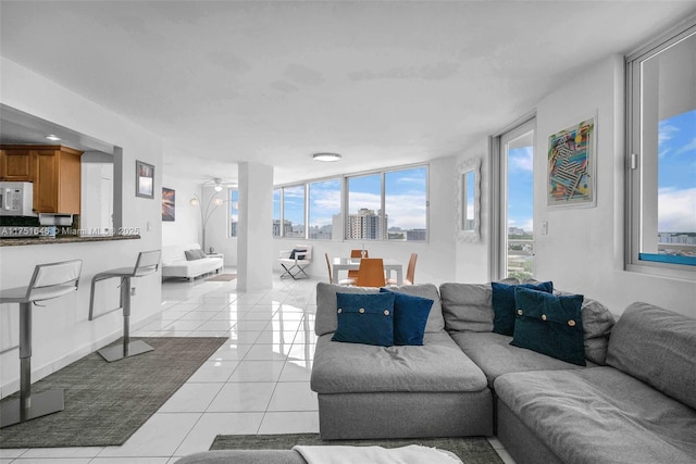 living area with light tile patterned floors, ceiling fan, and a view of city