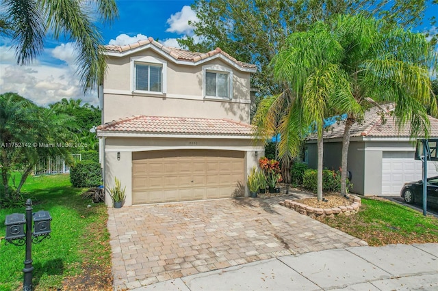 view of front facade featuring decorative driveway, an attached garage, a tile roof, and stucco siding