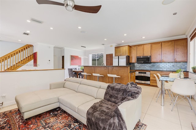 living area featuring ornamental molding, visible vents, ceiling fan, and light tile patterned floors