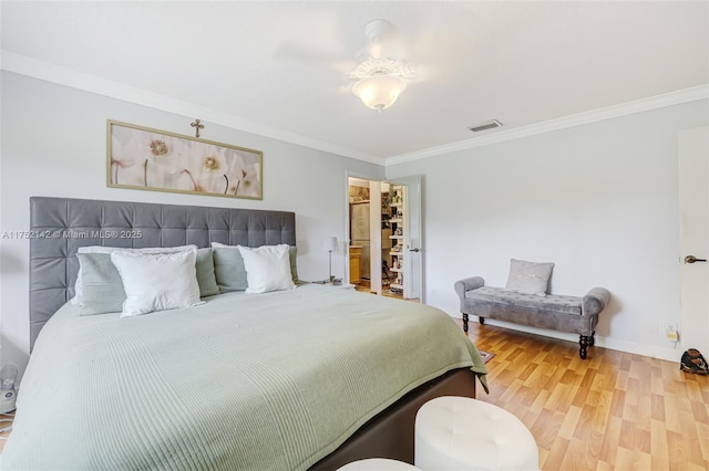 bedroom with visible vents, crown molding, baseboards, and wood finished floors