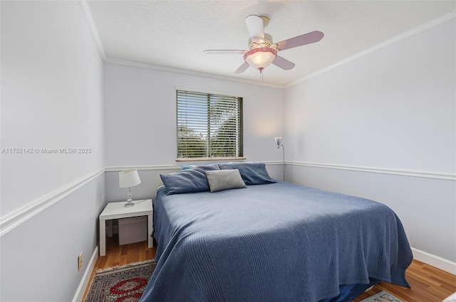 bedroom with crown molding, a textured ceiling, a ceiling fan, and wood finished floors