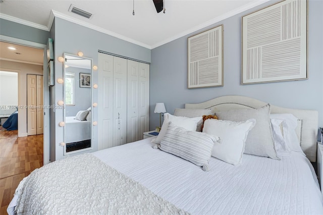 bedroom with a closet, visible vents, crown molding, and wood finished floors