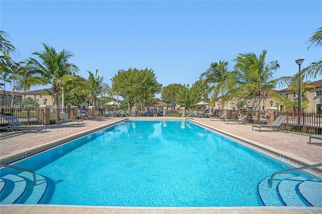 pool featuring a patio area, fence, and a residential view