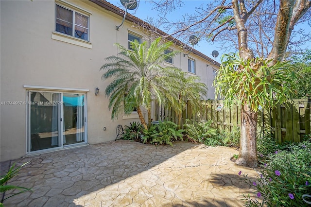 rear view of property featuring a patio area, fence, a tiled roof, and stucco siding