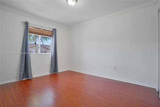 spare room with baseboards, wood finished floors, and crown molding