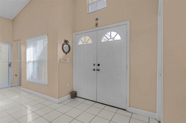 entrance foyer featuring light tile patterned floors, visible vents, a high ceiling, and baseboards