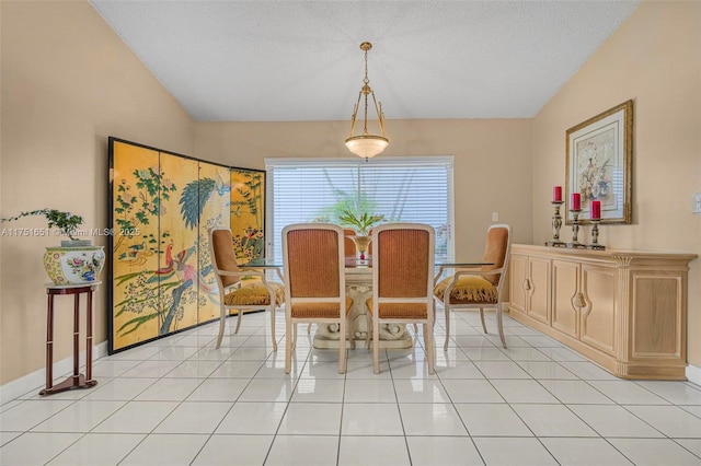 dining room with baseboards, vaulted ceiling, a textured ceiling, and light tile patterned flooring