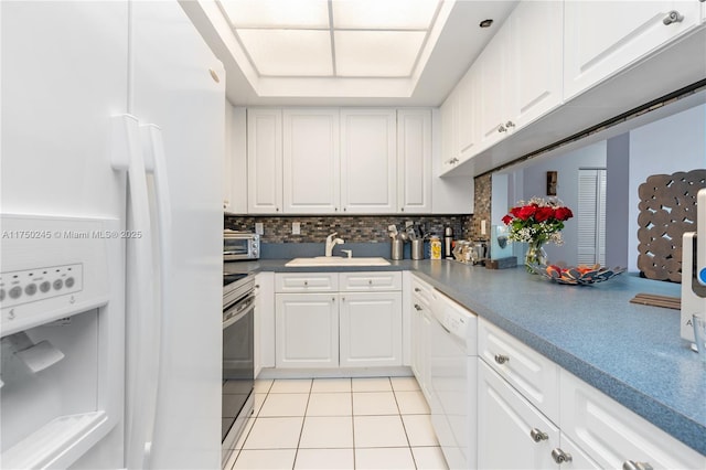 kitchen featuring white appliances, light tile patterned flooring, a sink, and white cabinetry