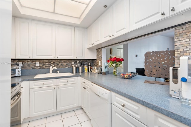 kitchen with tasteful backsplash, white dishwasher, white cabinetry, and a sink