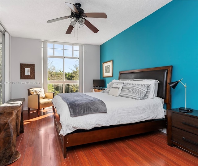 bedroom with a textured ceiling, wood finished floors, a ceiling fan, and floor to ceiling windows