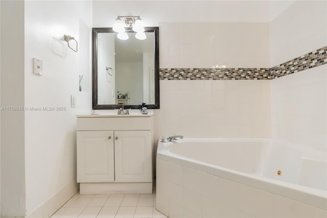 bathroom with a tub with jets, vanity, and tile patterned floors