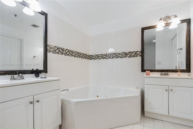 full bathroom with two vanities, a sink, visible vents, tile patterned floors, and a tub with jets