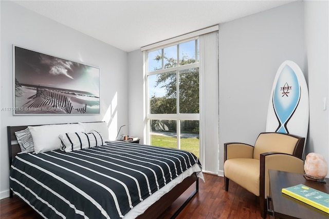 bedroom featuring baseboards, wood finished floors, and floor to ceiling windows