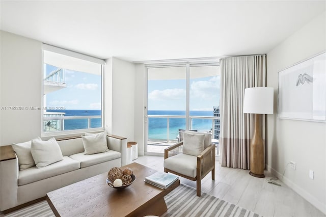 living area with light wood-style floors, a water view, and baseboards