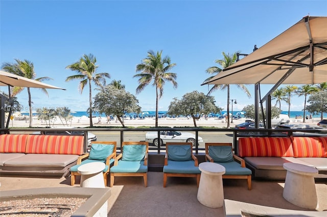 view of patio with a view of the beach, a water view, a balcony, and an outdoor living space