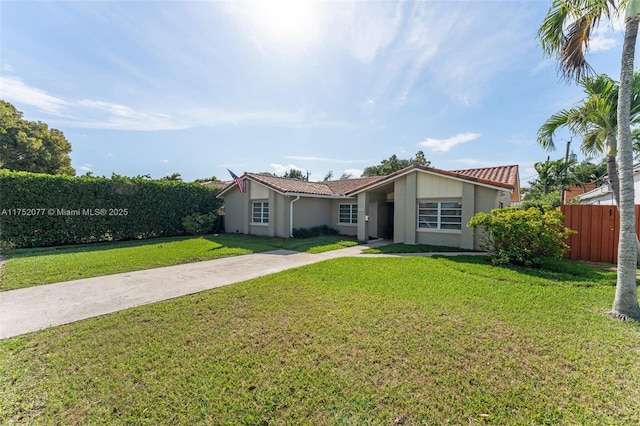 view of front of house with a front lawn, a tile roof, and fence