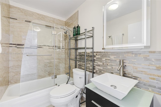 bathroom featuring tile walls, bath / shower combo with glass door, toilet, wainscoting, and vanity