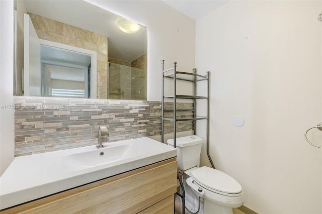 bathroom with backsplash, a tile shower, vanity, and toilet