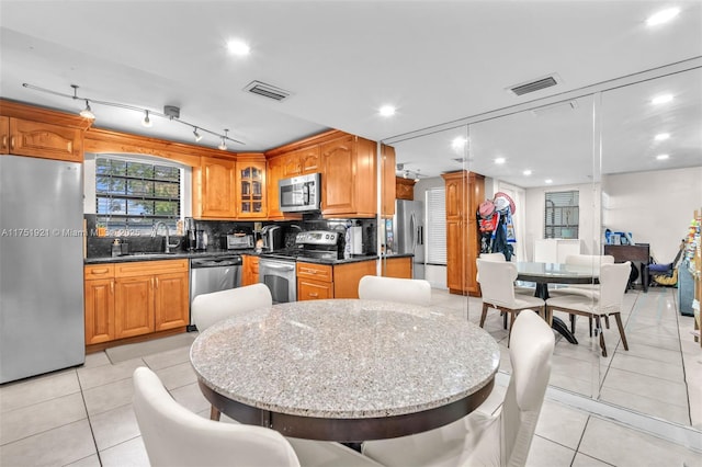 kitchen with visible vents, glass insert cabinets, appliances with stainless steel finishes, a sink, and light tile patterned flooring