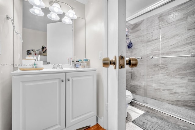 full bathroom with toilet, a stall shower, and vanity