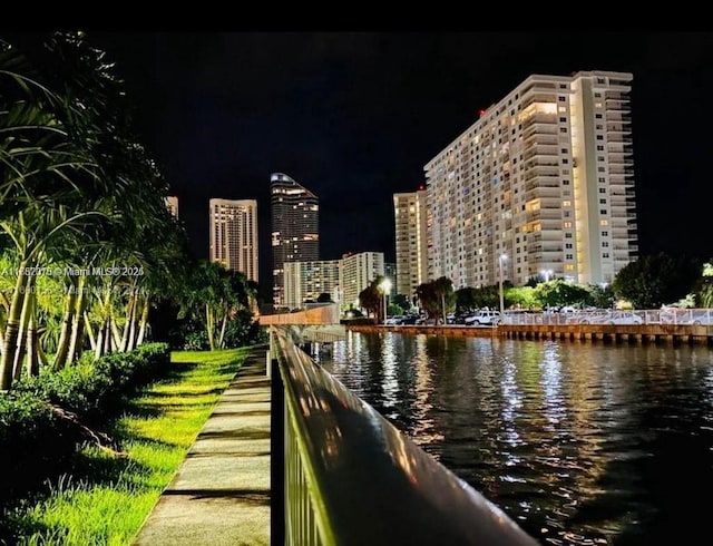 view of property's community with a water view and a view of city lights