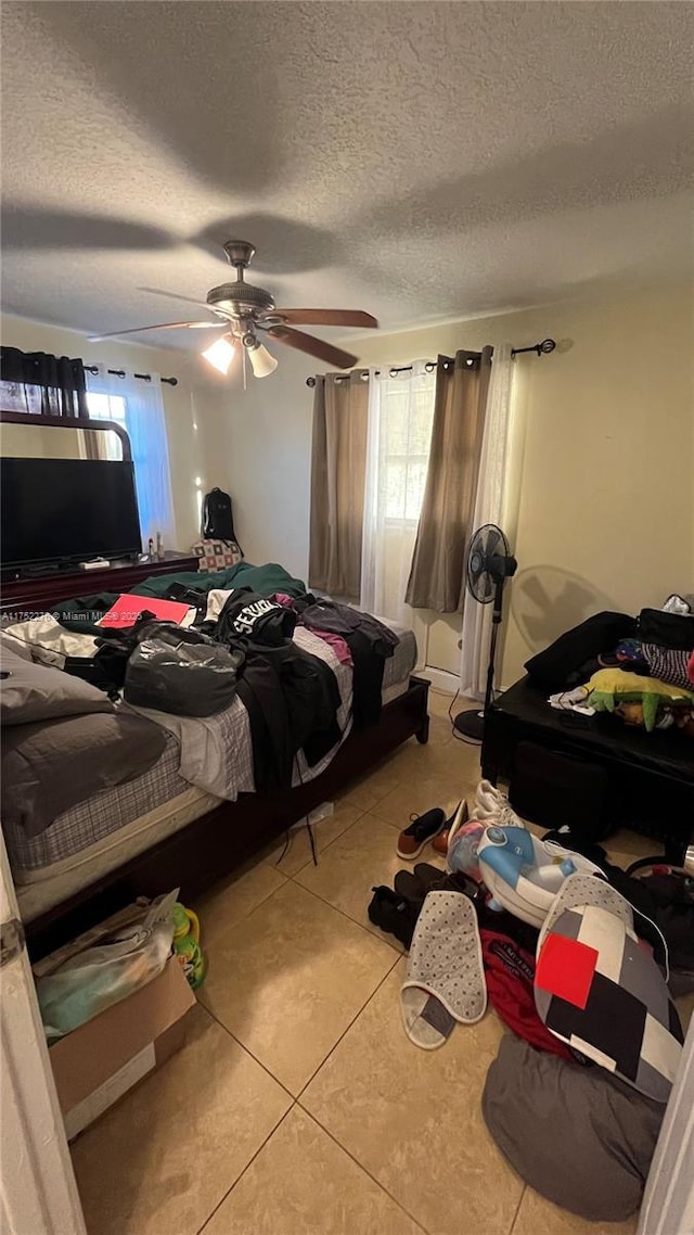 bedroom with ceiling fan, a textured ceiling, and light tile patterned flooring