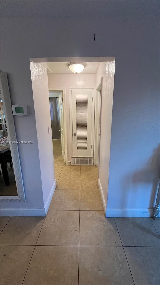 corridor featuring light tile patterned flooring and baseboards