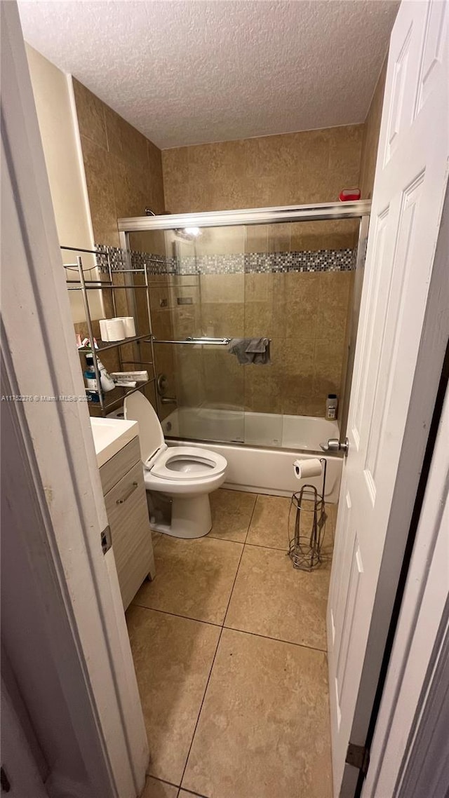 full bathroom with a textured ceiling, toilet, vanity, and tile patterned floors