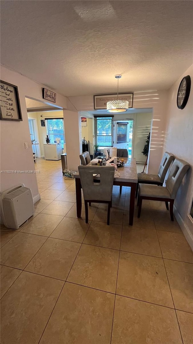 dining area with a textured ceiling and light tile patterned floors