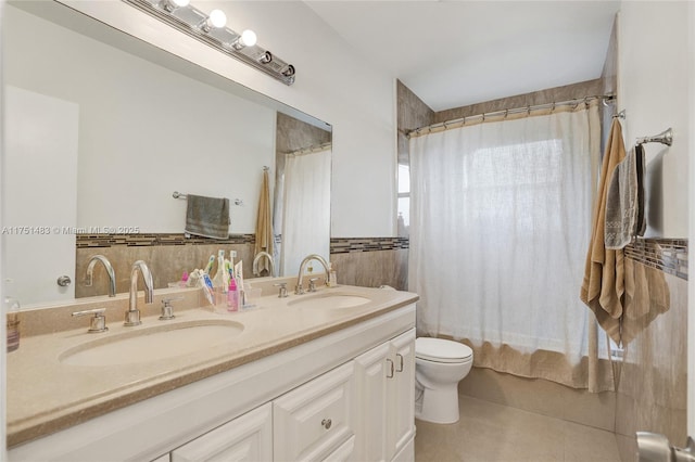 bathroom featuring shower / bathtub combination with curtain, a sink, tile walls, and double vanity