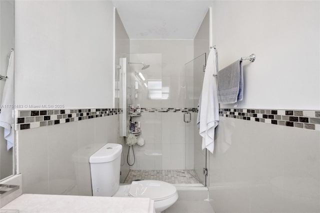 full bathroom featuring toilet, a stall shower, tile walls, and a wainscoted wall