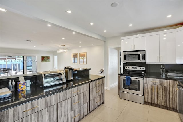 kitchen with light tile patterned floors, a toaster, stainless steel appliances, white cabinetry, and modern cabinets