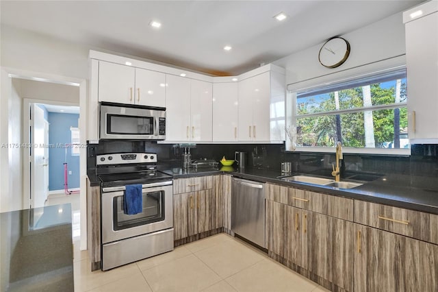 kitchen featuring stainless steel appliances, a sink, white cabinets, tasteful backsplash, and modern cabinets