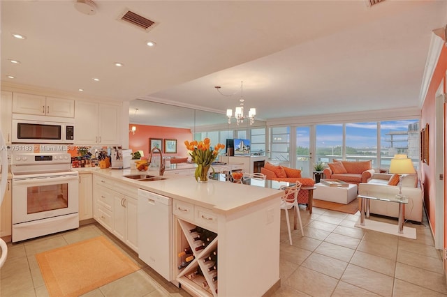 kitchen featuring light countertops, open floor plan, a sink, white appliances, and a peninsula