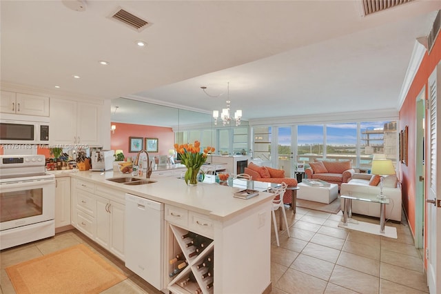 kitchen with white appliances, visible vents, a peninsula, light countertops, and a sink