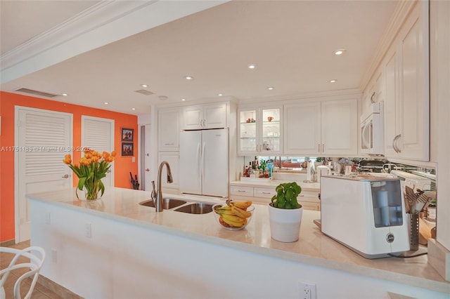 kitchen with light countertops, glass insert cabinets, white cabinetry, a sink, and white appliances