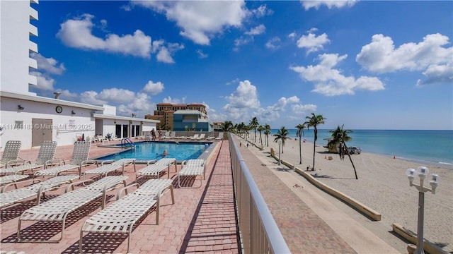 community pool featuring a water view, a patio area, and a view of the beach