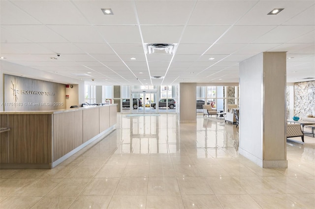 interior space featuring light tile patterned floors, a paneled ceiling, visible vents, open floor plan, and modern cabinets