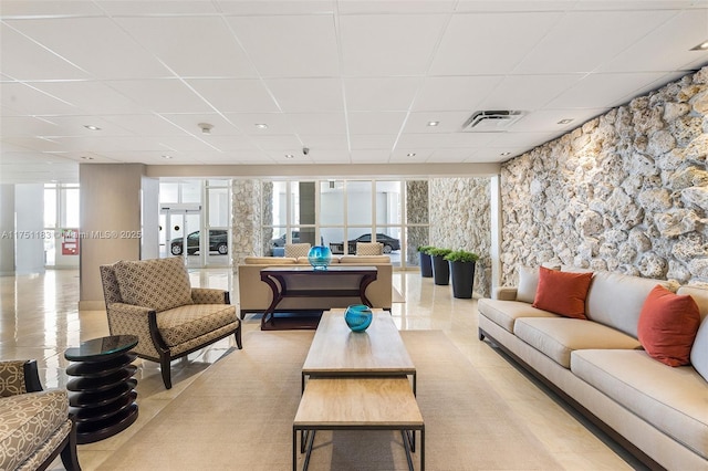 living area with light tile patterned flooring, a drop ceiling, and visible vents