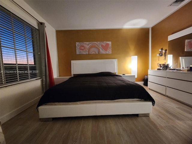 bedroom featuring visible vents, baseboards, and wood finished floors