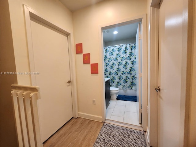 hall with baseboards and light wood-type flooring