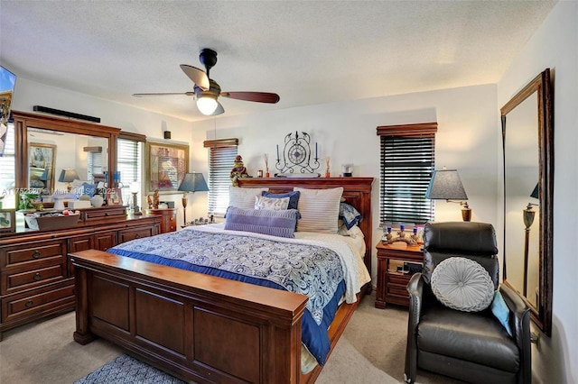 bedroom featuring a ceiling fan, light carpet, and a textured ceiling