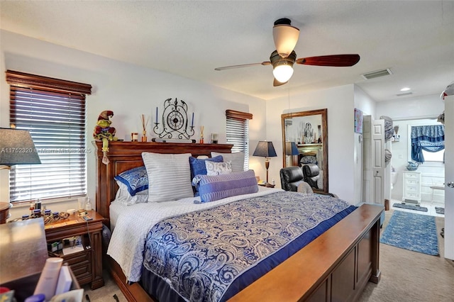 bedroom with connected bathroom, visible vents, a ceiling fan, and light colored carpet