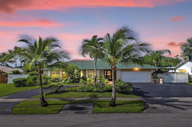 view of front of property with aphalt driveway, fence, and a garage