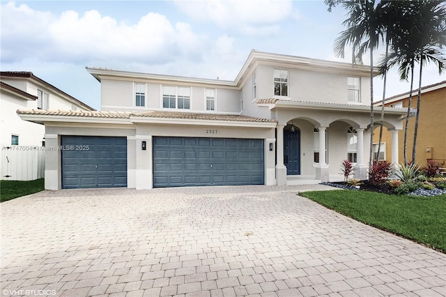 view of front of home with decorative driveway, stucco siding, a porch, fence, and a garage