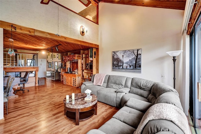 living room with beam ceiling, high vaulted ceiling, track lighting, and wood finished floors