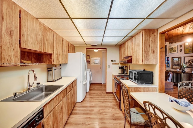 kitchen featuring range with electric cooktop, a sink, washer and dryer, light countertops, and dishwasher