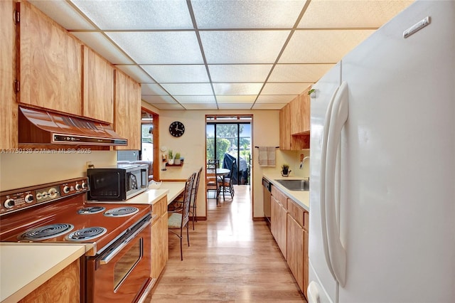 kitchen featuring light countertops, stove, a sink, and freestanding refrigerator